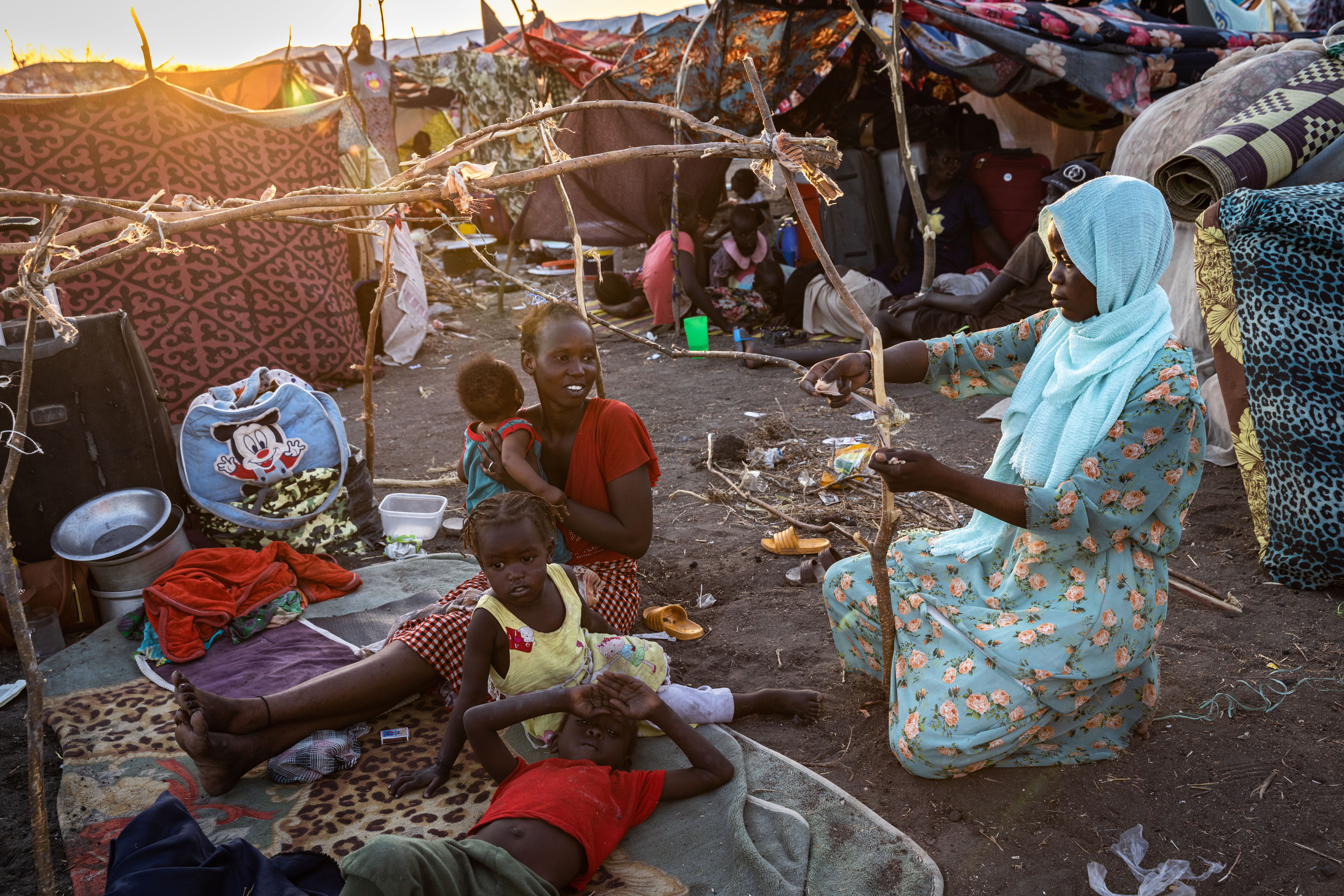 Recém-regressada do Sudão, Eliza (de top vermelho) é ajudada por um vizinho a construir um abrigo no centro de trânsito do ACNUR perto da fronteira em Renk. Eliza planeia regressar a Bentiu, de onde fugiu em 2013
