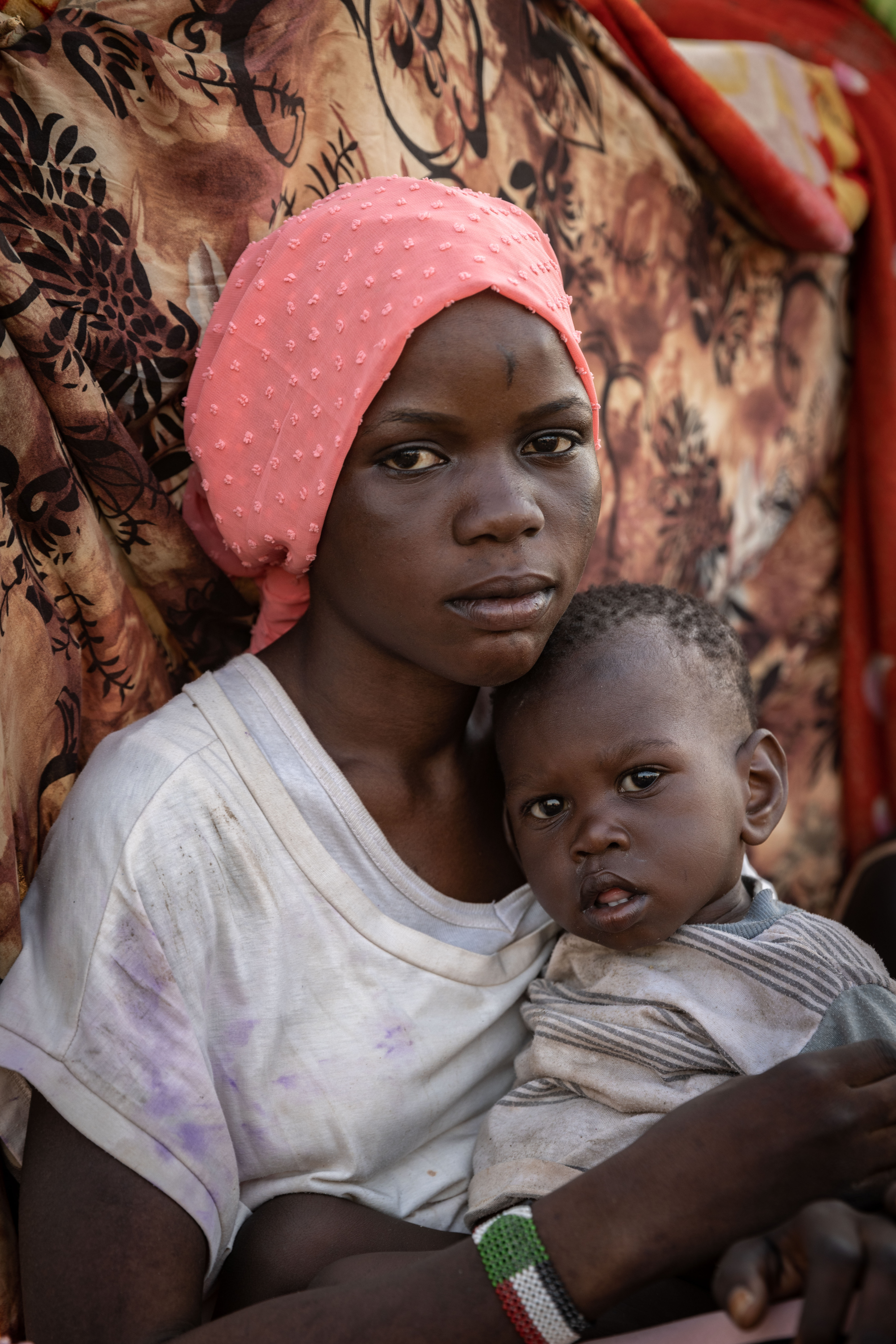 Nyauke Chianjiak, 18 anos, retornada do Sudão do Sul, senta-se com a sua irmã de um ano, Kuoli, num centro de trânsito em Renk, Sudão do Sul, depois de ter fugido do conflito no Sudão. 