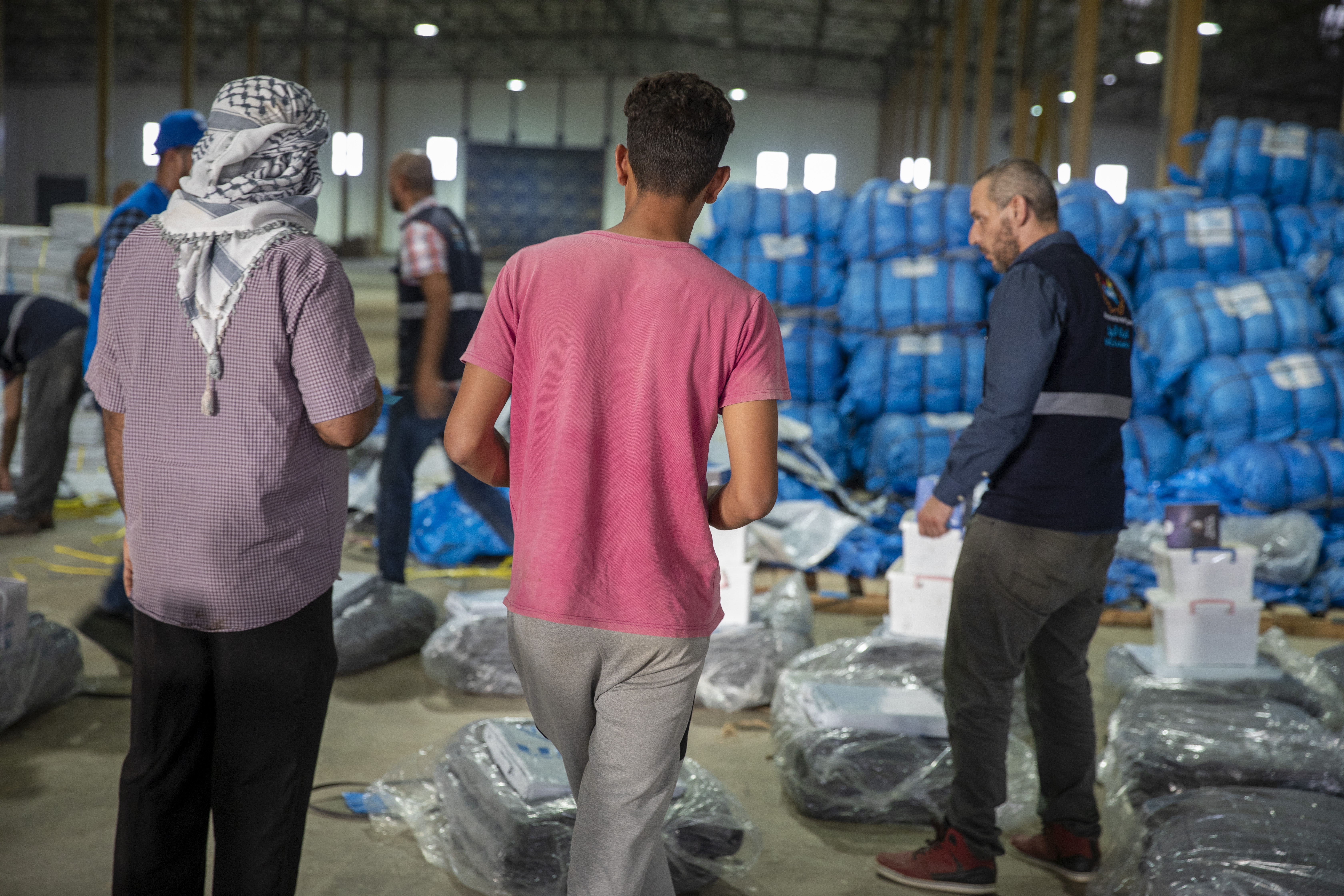 Pessoas deslocadas pelas cheias esperam para receber cobertores e outros artigos de socorro no centro de distribuição em Al Marj