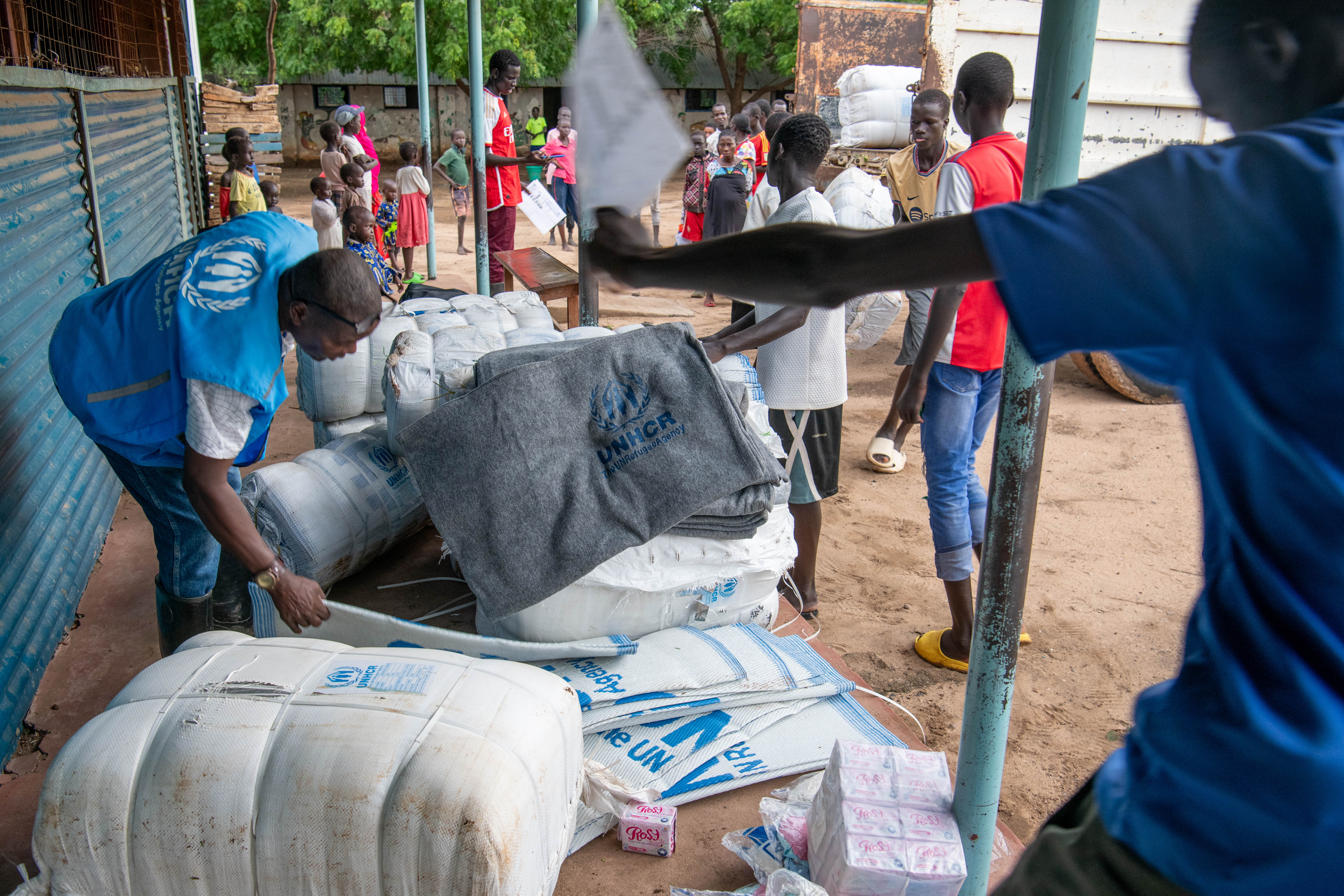 Um membro do pessoal do ACNUR distribui artigos de emergência aos refugiados deslocados pelas cheias na colónia de refugiados de Kakuma, no Quénia. © UNHCR/Eric Bakuli 